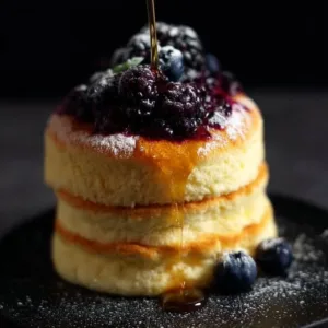 Fluffy Japanese soufflé pancakes stacked with syrup and berries