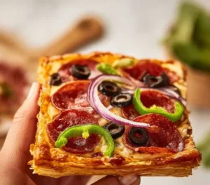 Delicious puff pastry pizza topped with melted cheese and fresh vegetables