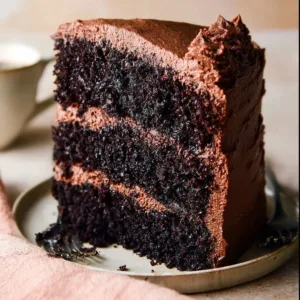 Ina Garten's rich and moist chocolate cake served on a rustic wooden table.